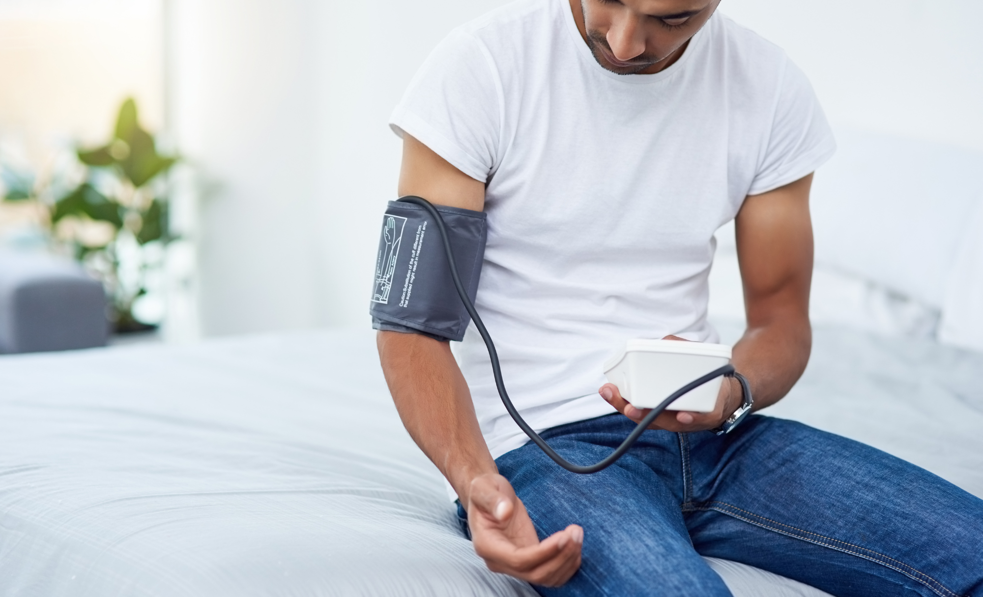 A man sitting down with a blood pressure monitor on his arm.